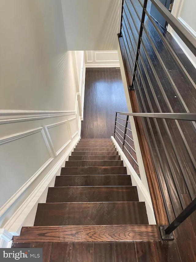 stairway with a wainscoted wall, hardwood / wood-style floors, and a decorative wall