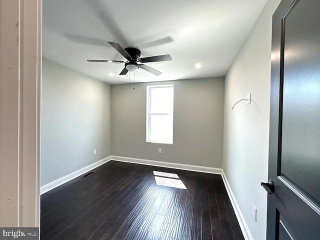 empty room featuring a ceiling fan, baseboards, visible vents, and dark wood-style floors