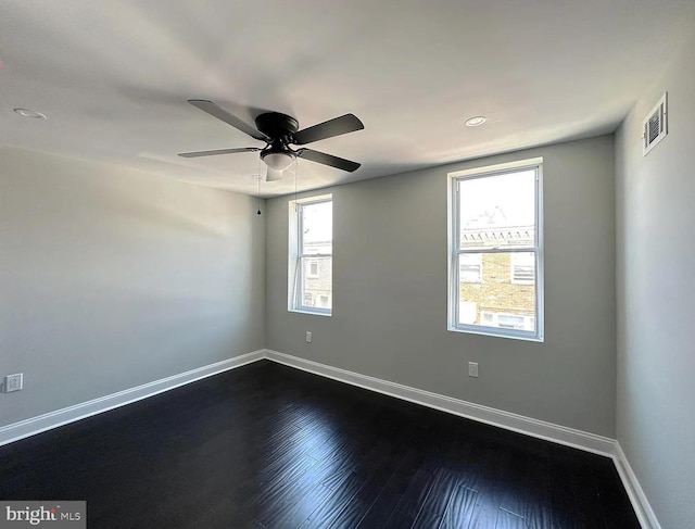 empty room featuring visible vents, baseboards, ceiling fan, and dark wood finished floors