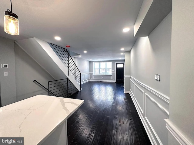 interior space with dark wood-style flooring, a decorative wall, a wainscoted wall, stairs, and recessed lighting