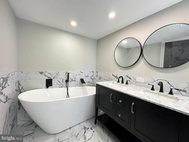 full bathroom with a sink, tile walls, a freestanding tub, and marble finish floor