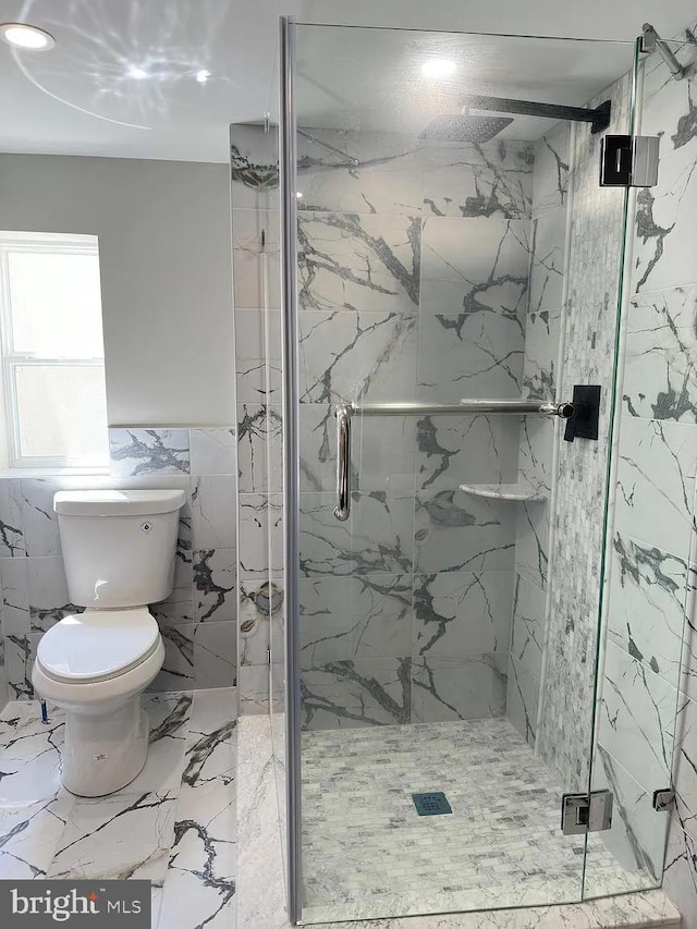 bathroom featuring a marble finish shower, toilet, tile walls, and marble finish floor