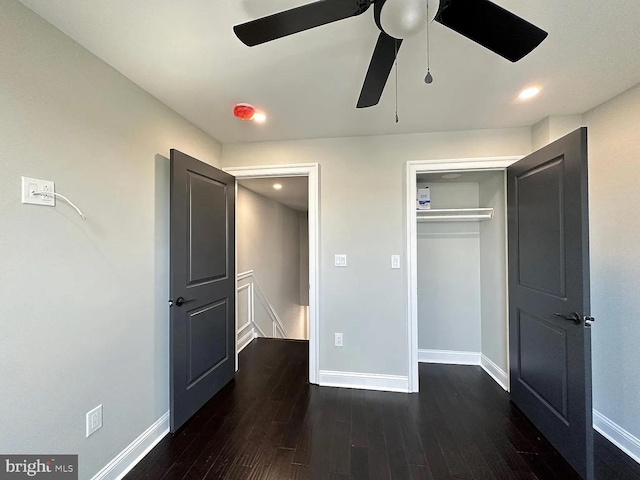 unfurnished bedroom with a closet, baseboards, a ceiling fan, and dark wood-type flooring