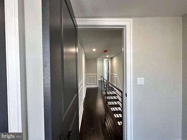 corridor with dark wood-style flooring, an upstairs landing, recessed lighting, and a decorative wall