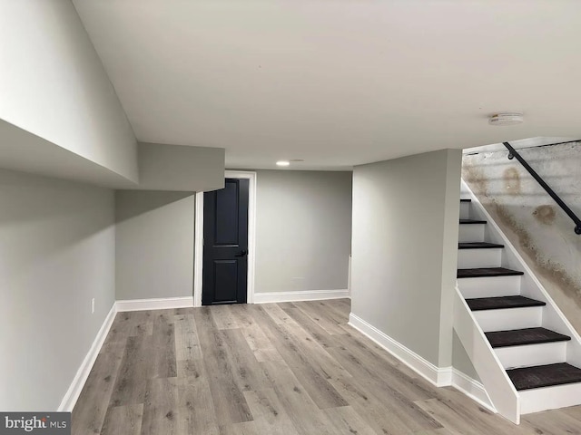 finished basement featuring recessed lighting, baseboards, stairs, and wood finished floors
