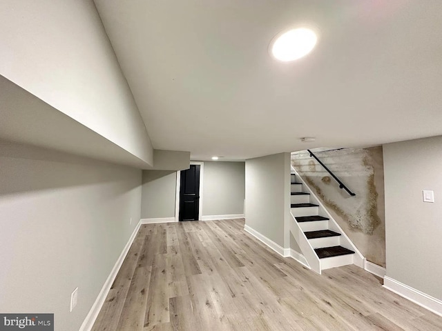 finished basement with light wood-style floors, baseboards, and stairs