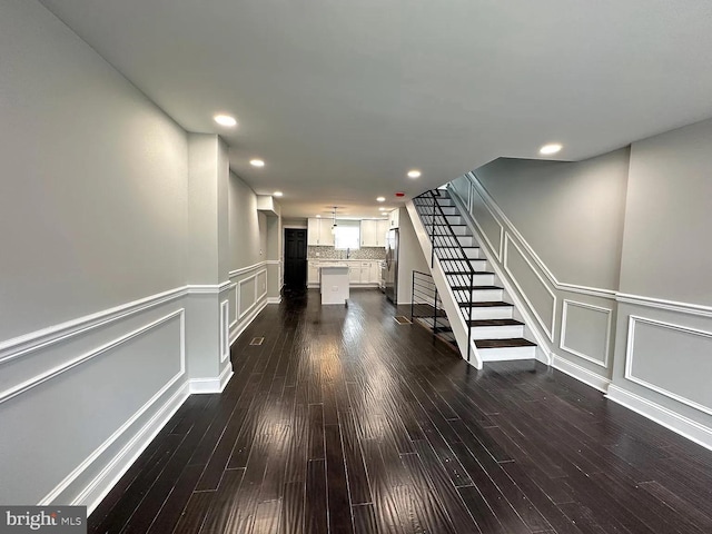 interior space with stairway, a decorative wall, and dark wood-style floors