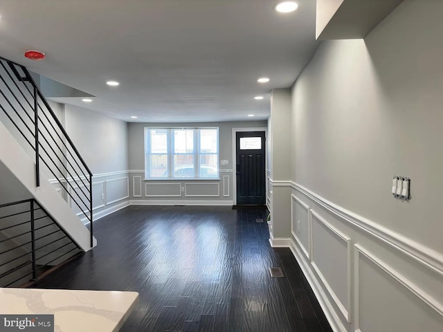entrance foyer featuring recessed lighting, a decorative wall, stairs, and dark wood-style floors