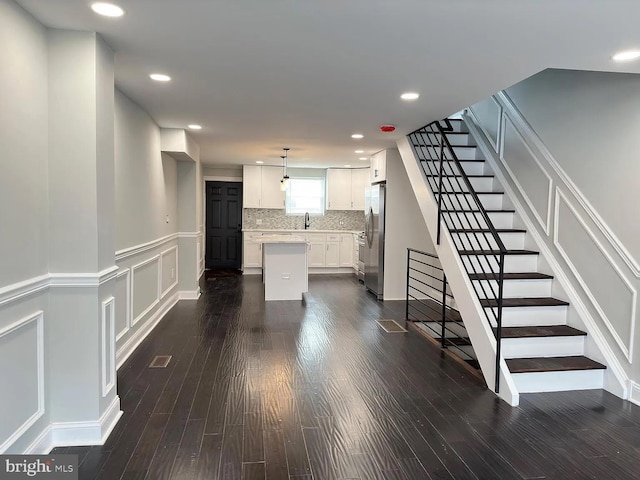 interior space with a wainscoted wall, a decorative wall, recessed lighting, and wood finished floors