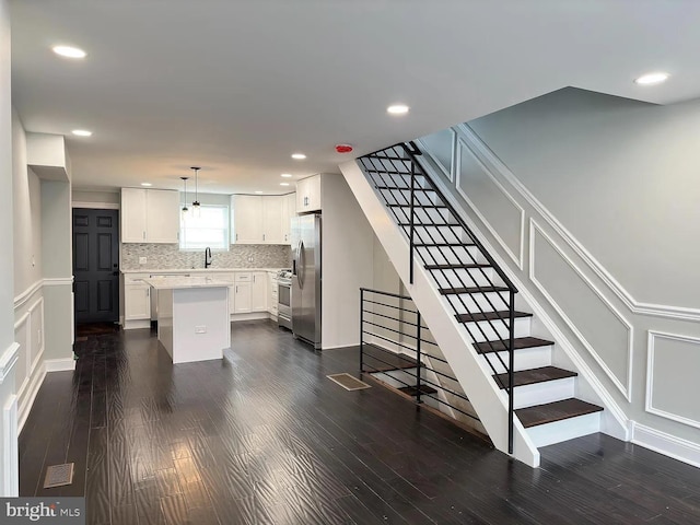 kitchen featuring a decorative wall, a kitchen island, stainless steel appliances, and dark wood finished floors