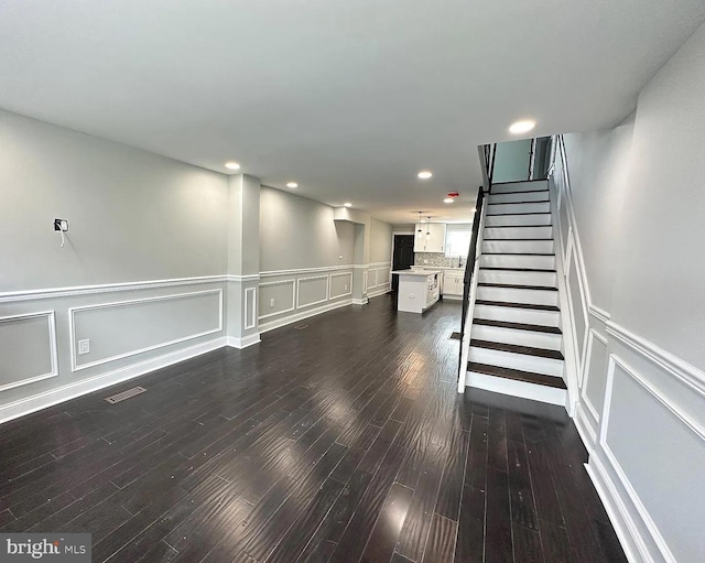 interior space featuring visible vents, stairs, a decorative wall, a wainscoted wall, and dark wood finished floors
