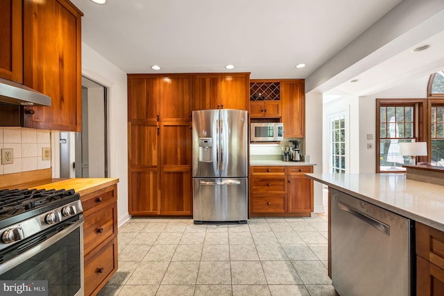 kitchen featuring tasteful backsplash, stainless steel appliances, under cabinet range hood, and recessed lighting