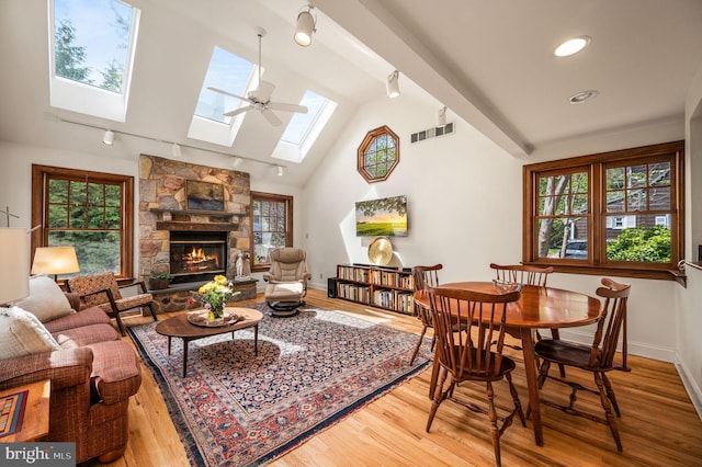 interior space with lofted ceiling with skylight, visible vents, rail lighting, and wood finished floors