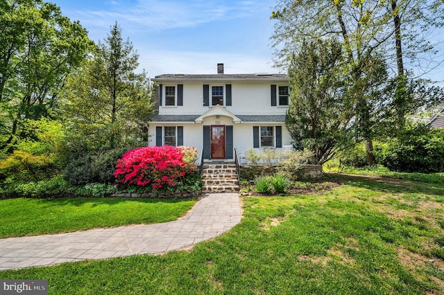 view of front of home with a front lawn, stucco siding, and a chimney