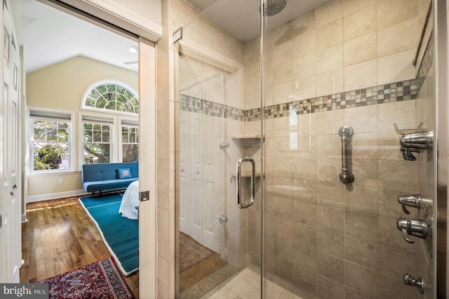 full bath with baseboards, wood finished floors, a shower stall, and lofted ceiling