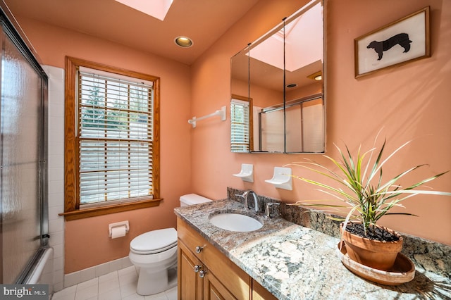 bathroom with toilet, recessed lighting, vanity, tile patterned flooring, and a skylight