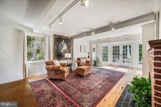 interior space featuring rail lighting, wood finished floors, french doors, and baseboards