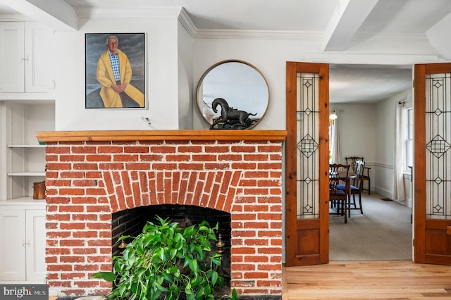 interior details featuring wood finished floors, ornamental molding, and a brick fireplace