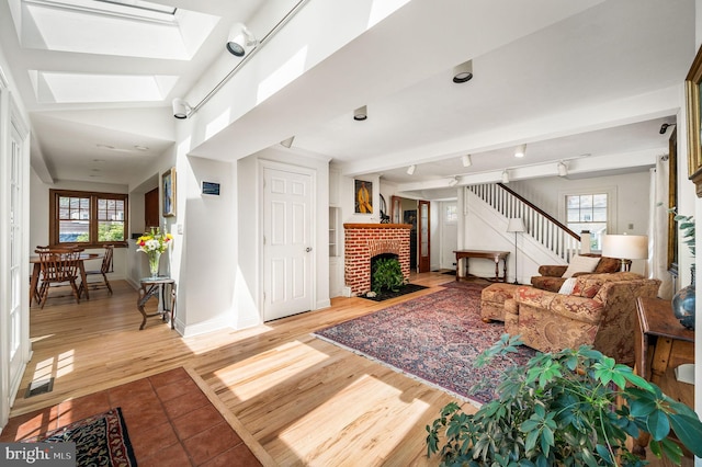 living room featuring a fireplace, a skylight, wood finished floors, and a healthy amount of sunlight