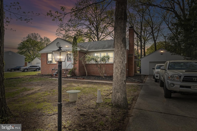 bungalow with an outdoor structure, a chimney, a detached garage, and brick siding