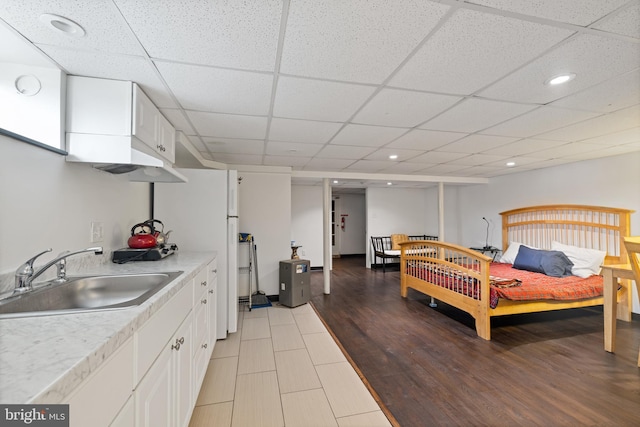 bedroom with a drop ceiling, recessed lighting, freestanding refrigerator, and a sink