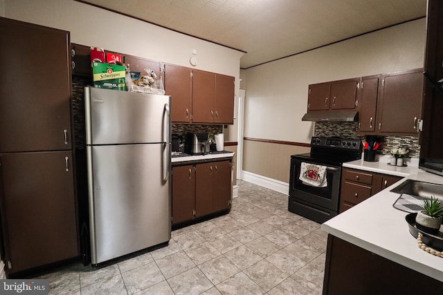 kitchen with tasteful backsplash, freestanding refrigerator, light tile patterned floors, electric range, and under cabinet range hood