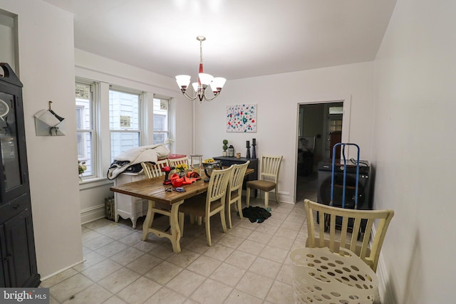 dining area featuring light tile patterned floors, a notable chandelier, and baseboards