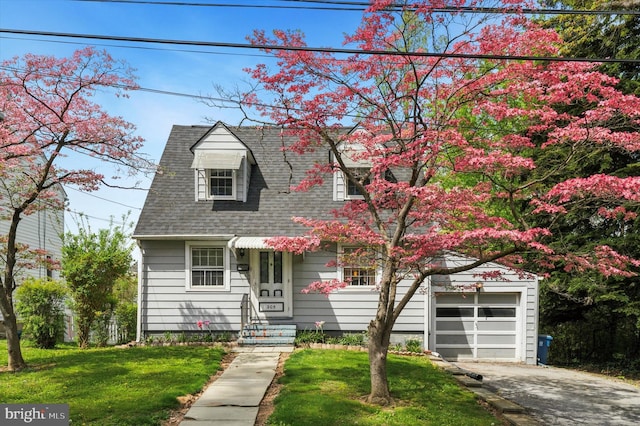 cape cod home with aphalt driveway, roof with shingles, a front yard, and a garage