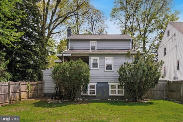 back of property featuring a chimney, a yard, and a fenced backyard