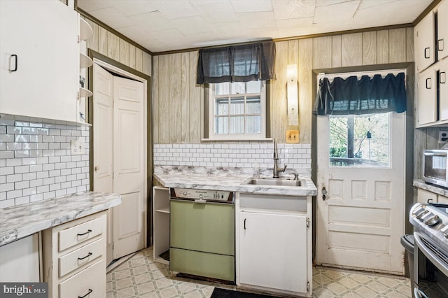 kitchen with wood walls, dishwashing machine, tasteful backsplash, and a sink