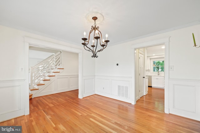 9373 Robnel Pl, Vienna, VA 22182 - unfurnished dining area with visible vents, a notable chandelier, light wood-style floors, a decorative wall, and stairs