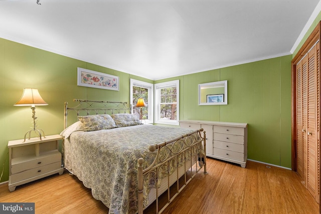 bedroom featuring crown molding, baseboards, a closet, and wood finished floors