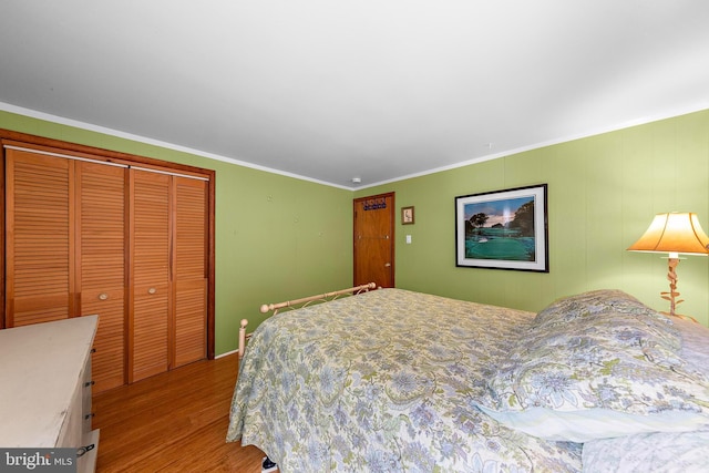 bedroom with baseboards, ornamental molding, wood finished floors, and a closet