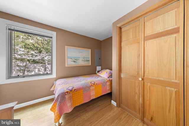 bedroom with baseboards, a closet, and light wood finished floors