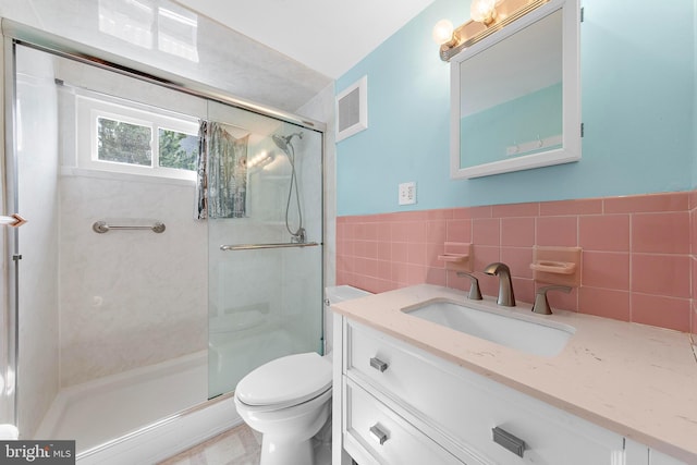 full bath featuring visible vents, vanity, toilet, tile walls, and a shower stall