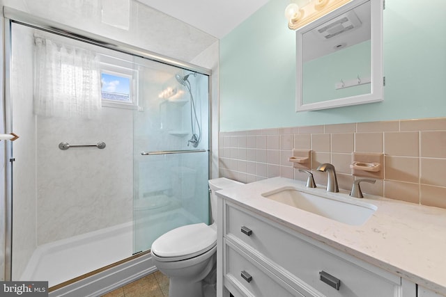 full bath with visible vents, tile walls, a stall shower, vanity, and toilet