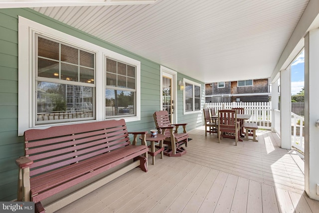 deck featuring fence, covered porch, and outdoor dining space