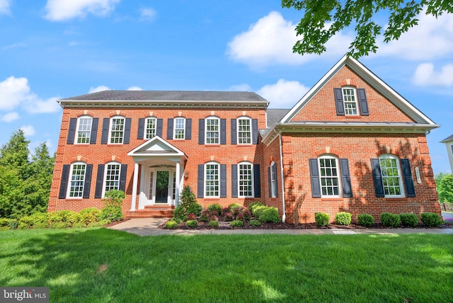 georgian-style home with a front lawn and brick siding