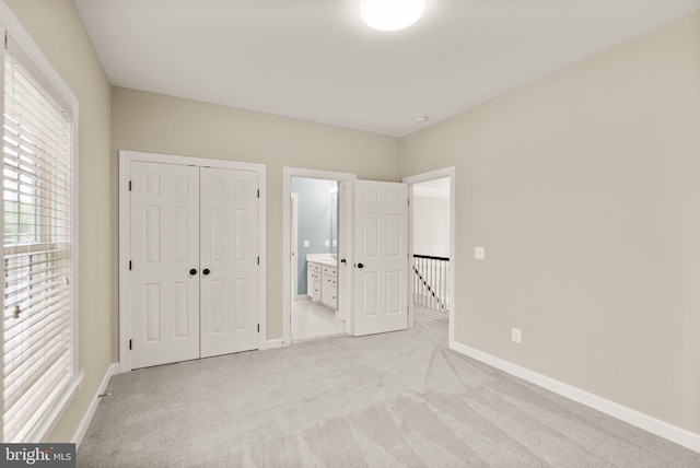 unfurnished bedroom featuring light carpet, baseboards, a closet, and connected bathroom