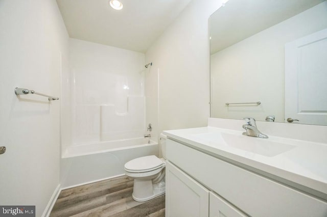 full bath featuring baseboards, toilet, shower / bath combination, wood finished floors, and vanity