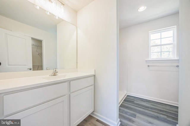 bathroom with vanity, recessed lighting, wood finished floors, and baseboards