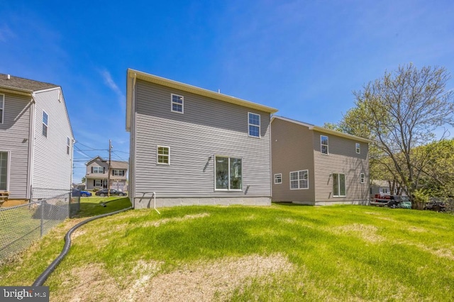 back of property featuring fence and a lawn