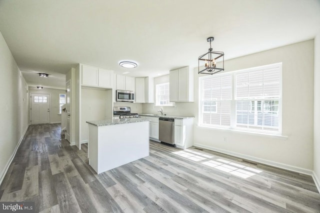 kitchen featuring a chandelier, stainless steel appliances, white cabinets, and baseboards