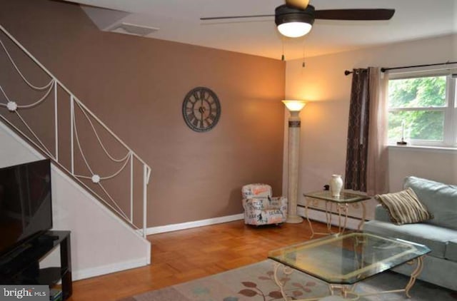living area featuring ceiling fan, baseboards, stairway, and a baseboard radiator
