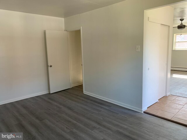 empty room with baseboard heating, baseboards, and dark wood finished floors