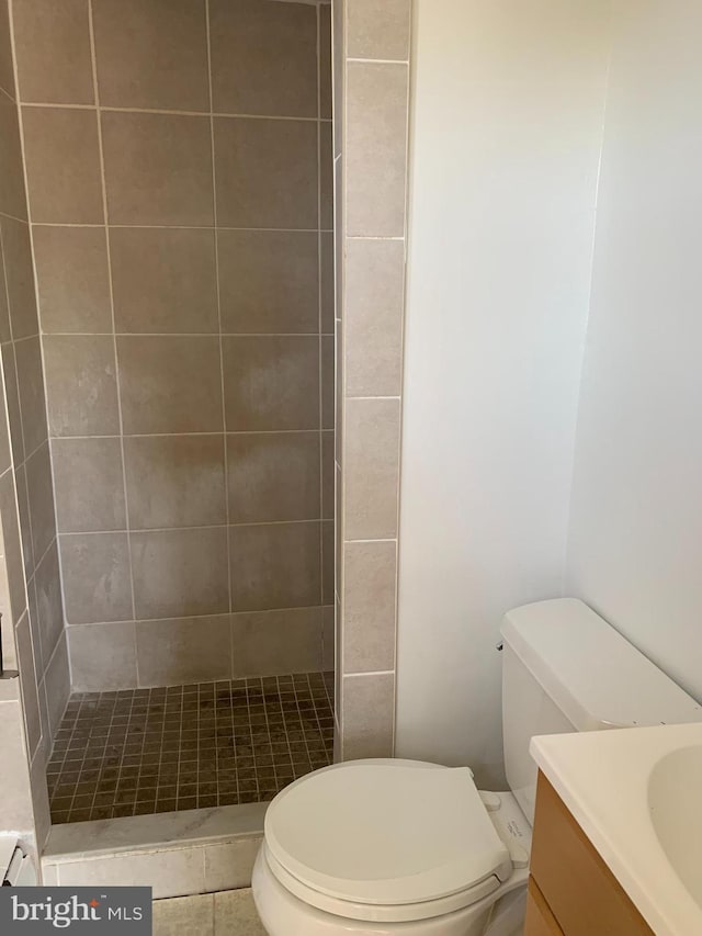 full bathroom with toilet, tiled shower, and vanity