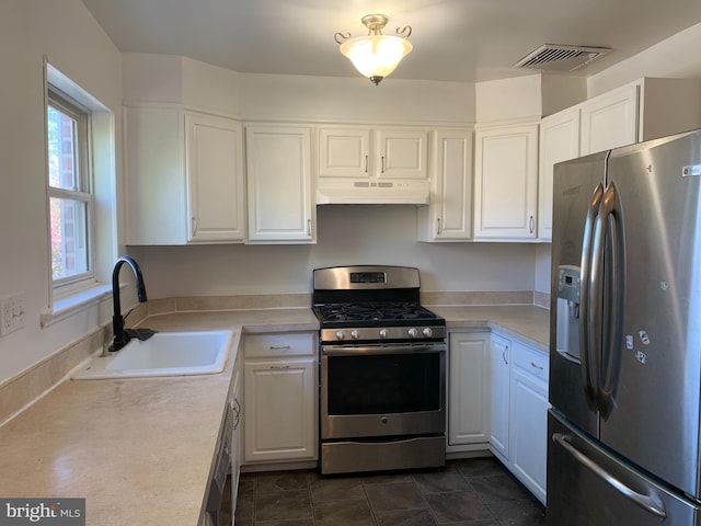 kitchen featuring white cabinetry, a sink, visible vents, stainless steel appliances, and under cabinet range hood