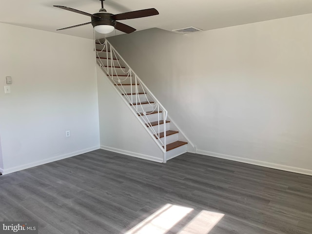 interior space with dark wood-type flooring, a ceiling fan, baseboards, and stairs