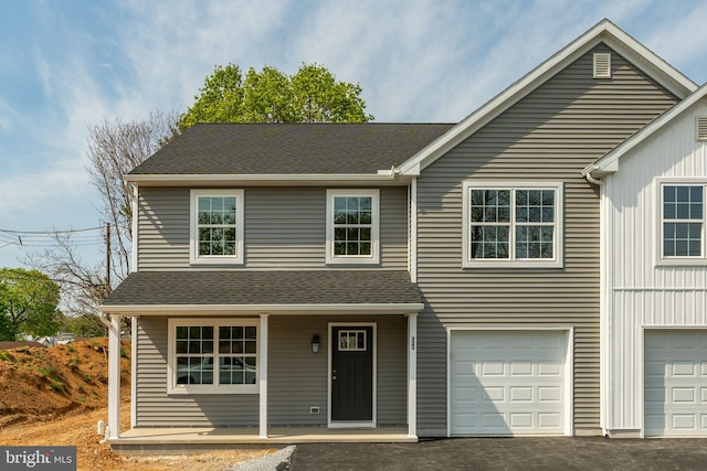 view of front facade with a shingled roof, an attached garage, covered porch, and aphalt driveway