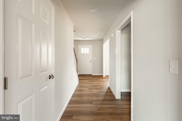 corridor with stairs, baseboards, and dark wood-type flooring